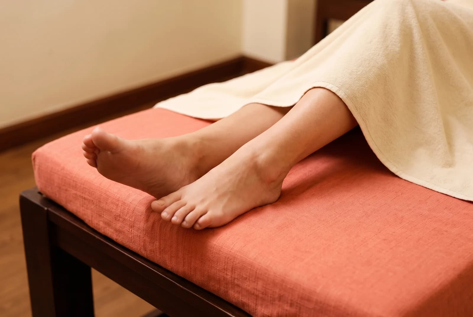 Feet and lower legs resting on a treatment couch under a cream drape