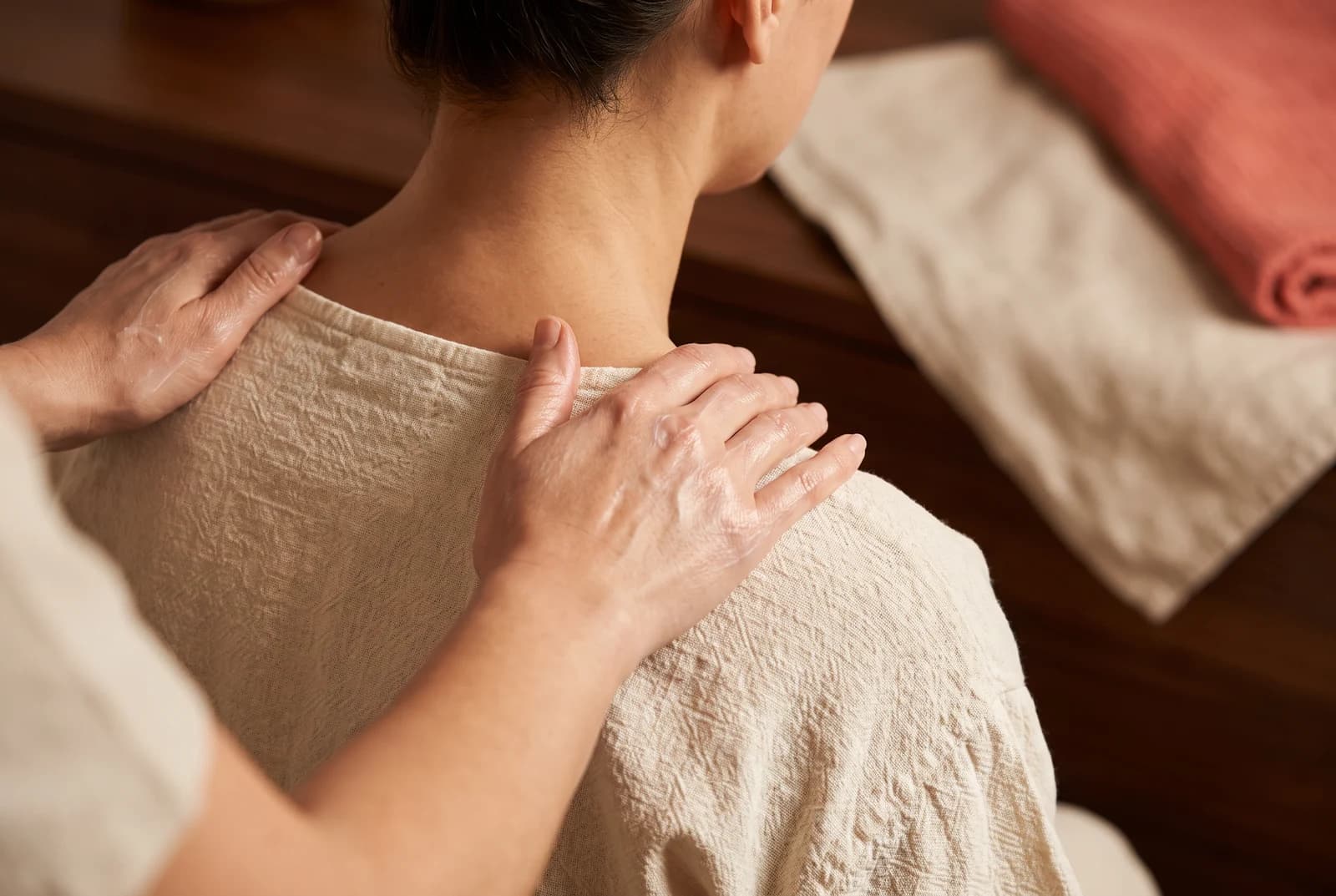 Gentle hands resting on the shoulders of a clothed seated guest