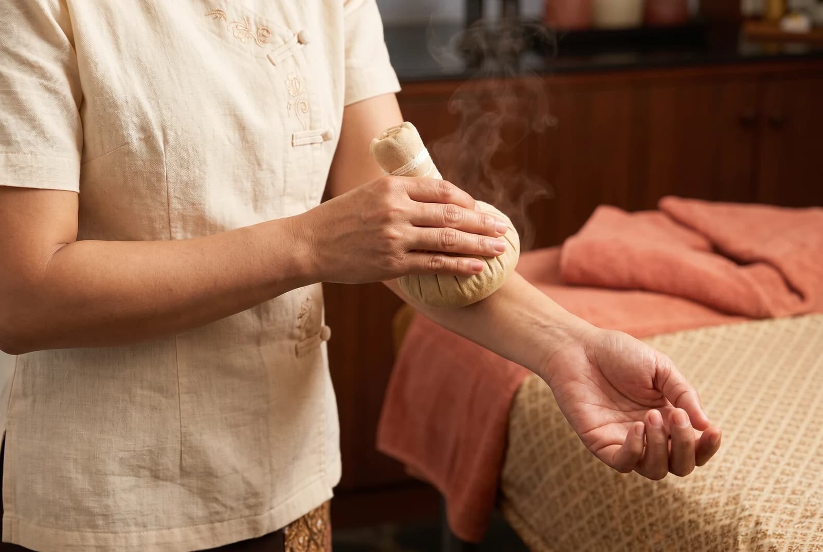 Practitioner checking a herbal compress against their forearm